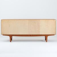 Johannes Andersenがデザインし、C.F.C. Silkeborgが製作した幅200cmのサイドボードです。チーク材の豊かな木目を活かした滑らかな曲面フレームと、横へ流れるように開閉する蛇腹扉が印象的で、端正さの中に軽やかなリズムを生み出します。中央の4段引き出しと両側の収納スペースにより高い収納力を備え、内部の棚板は可動式で実用性も良好。すらりと伸びる脚部が全体に洗練された印象を与え、空間に北欧ビンテージならではの気品と存在感をもたらします。