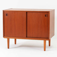 チーク材とビーチ材を組み合わせた北欧ビンテージのローボードで、直線的で端正なフォルムの中に素材の表情が美しく表れた一台です。引き戸仕様の前面は空間をすっきりと見せ、コンパクトなサイズ感ながら内部は左右に分かれた収納構造で、オーディオ機器や書類、小物類まで整理しやすい設計です。脚付き構造による軽やかな佇まいと、経年によって深みを増した木肌の風合いが、当時の丁寧なつくりとビンテージならではの存在感を感じさせ、リビングや書斎、寝室の収納家具として幅広く活躍します。