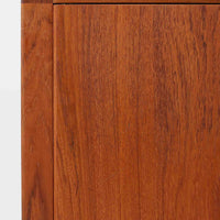 レナート・ベンダーがデザインし、Ulferts Mobler社により製作されたCoronaキャビネットは、小ぶりなサイズ感と端正な佇まいが魅力の北欧ビンテージ家具です。チーク材の美しい木目を活かしたシンプルな箱型構造に、脚部の控えめな意匠が軽やかさを添えています。取っ手部分には異素材となるローズウッドが用いられており、チーク材とのコントラストがさりげないアクセントとして全体の表情を引き締めています。内部は使いやすい収納空間を備え、食器や書類、小物類の整理に適しており、リビングや書斎、玄関周りなど幅広いシーンで活躍します。年月を経て深みを増した素材感と、丁寧な作りが感じられる一台です。