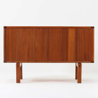 レナート・ベンダーがデザインし、Ulferts Mobler社により製作されたCoronaキャビネットは、小ぶりなサイズ感と端正な佇まいが魅力の北欧ビンテージ家具です。チーク材の美しい木目を活かしたシンプルな箱型構造に、脚部の控えめな意匠が軽やかさを添えています。取っ手部分には異素材となるローズウッドが用いられており、チーク材とのコントラストがさりげないアクセントとして全体の表情を引き締めています。内部は使いやすい収納空間を備え、食器や書類、小物類の整理に適しており、リビングや書斎、玄関周りなど幅広いシーンで活躍します。年月を経て深みを増した素材感と、丁寧な作りが感じられる一台です。