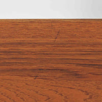 レナート・ベンダーがデザインし、Ulferts Mobler社により製作されたCoronaキャビネットは、小ぶりなサイズ感と端正な佇まいが魅力の北欧ビンテージ家具です。チーク材の美しい木目を活かしたシンプルな箱型構造に、脚部の控えめな意匠が軽やかさを添えています。取っ手部分には異素材となるローズウッドが用いられており、チーク材とのコントラストがさりげないアクセントとして全体の表情を引き締めています。内部は使いやすい収納空間を備え、食器や書類、小物類の整理に適しており、リビングや書斎、玄関周りなど幅広いシーンで活躍します。年月を経て深みを増した素材感と、丁寧な作りが感じられる一台です。