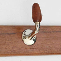 チーク材のベースにメタルフックを組み合わせたデンマーク製の2連ウォールハンガーで、先端には丸みのある木製キャップが付いており掛けた衣類やバッグに優しく、シンプルながら北欧ビンテージらしい温かみのある素材感が魅力です。玄関や寝室、キッチン、ワークスペースなど壁面収納として幅広く活躍し、単体使いはもちろん複数並べて設置することで統一感のあるディスプレイも楽しめます。コンパクトで設置しやすく暮らしの中で気軽に取り入れやすいアイテムです。