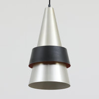 Jo HammerborgがFog & Morupのために手掛けた「Corona」は、直径22cmとコンパクトながら全高45cmと縦にしっかりとした存在感を持つアルミ×スチール製ペンダントライトで、上下に伸びる円錐形フォルムと中央のブラックバンドが彫刻的な印象を与える北欧ビンテージ品です。光源を囲む二重構造によって眩しさを抑えつつ下方向へ明かりを集中的に落とす設計となっており、ダイニングやカウンター上での1灯使用はもちろん、複数灯を並べても空間にリズムを生み出します。経年で深まった素材の風合いがハーマボーらしいモダンな佇まいを際立たせ、空間のアクセントとしても十分な存在感を発揮します。