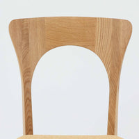 Niels Koefoedが1957年にデザインし、現在はCaso Furnitureより復刻製作されているモデル「Peter」のダイニングチェアです。オーク材の美しい木目を活かしたフレームと、背もたれに大きく設けられたアーチ状の開口部が印象的で、軽やかさと構造的な強度を両立したデザインが特徴です。身体をやさしく受け止める背のラインと、適度なクッション性を備えた座面により、日常使いにおいても快適な座り心地を実現しています。素材の質感を活かしたシンプルな佇まいは、ダイニング空間に自然と馴染み、北欧ミッドセンチュリー期のデザインらしい温かみと洗練を感じさせる一脚です。