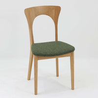 Niels Koefoedが1957年にデザインし、現在はCaso Furnitureより復刻製作されているモデル「Peter」のダイニングチェアです。オーク材の美しい木目を活かしたフレームと、背もたれに大きく設けられたアーチ状の開口部が印象的で、軽やかさと構造的な強度を両立したデザインが特徴です。身体をやさしく受け止める背のラインと、適度なクッション性を備えた座面により、日常使いにおいても快適な座り心地を実現しています。素材の質感を活かしたシンプルな佇まいは、ダイニング空間に自然と馴染み、北欧ミッドセンチュリー期のデザインらしい温かみと洗練を感じさせる一脚です。