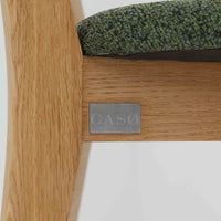 Niels Koefoedが1957年にデザインし、現在はCaso Furnitureより復刻製作されているモデル「Peter」のダイニングチェアです。オーク材の美しい木目を活かしたフレームと、背もたれに大きく設けられたアーチ状の開口部が印象的で、軽やかさと構造的な強度を両立したデザインが特徴です。身体をやさしく受け止める背のラインと、適度なクッション性を備えた座面により、日常使いにおいても快適な座り心地を実現しています。素材の質感を活かしたシンプルな佇まいは、ダイニング空間に自然と馴染み、北欧ミッドセンチュリー期のデザインらしい温かみと洗練を感じさせる一脚です。