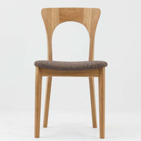 Niels Koefoedが1957年にデザインし、現在はCaso Furnitureより復刻製作されているモデル「Peter」のダイニングチェアです。オーク材の美しい木目を活かしたフレームと、背もたれに大きく設けられたアーチ状の開口部が印象的で、軽やかさと構造的な強度を両立したデザインが特徴です。身体をやさしく受け止める背のラインと、適度なクッション性を備えた座面により、日常使いにおいても快適な座り心地を実現しています。素材の質感を活かしたシンプルな佇まいは、ダイニング空間に自然と馴染み、北欧ミッドセンチュリー期のデザインらしい温かみと洗練を感じさせる一脚です。