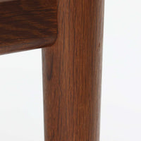 Hans J. Wegnerがデザインし、Getamaが製作したGE530オットマンです。ダークオーク材の力強い木目を活かした角の取れたフレームと、丸脚を組み合わせた端正な構造が特徴で、裏面には刻印も確認できます。程よい厚みのクッションは張り替え済みで、軽やかな生地が木部の深みのある色合いを引き立てます。同シリーズのラウンジチェアと合わせてはもちろん、単体でスツールや補助椅子としても活躍する、北欧ビンテージならではの質実剛健な一品です。