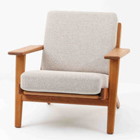 Hans J. Wegnerがデザインし、Getama社によって製作されたGE290は、構造の美しさと快適な座り心地を兼ね備えた北欧ビンテージを代表するシングルソファです。厚みのあるクッションと緩やかに傾斜した背もたれが身体を包み込み、自然と深いリラックス姿勢へと導きます。クッション内部にはビンテージ品ならではのスプリングが内包されており、しっかりとした弾力と安定感のある座り心地を生み出しています。オーク材のフレームは力強さと温かみを併せ持ち、アームから脚部にかけての造形にはウェグナーらしい彫刻的な魅力が感じられます。張地の落ち着いた色合いと、経年により深みを増した木部の表情が調和し、リビングや書斎で長く寄り添う一脚です。