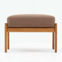 Hans J. Wegnerがデザインし、Getamaが製作したGE290オットマンです。オーク材の美しい木目を活かした無垢フレームは、丸みを帯びた脚部と貫構造により安定感と軽やかさを兼ね備えています。クッションは張り替え済みで、ライトブラウン色の張地が木部の温かな色合いと調和し、落ち着いた印象を与えます。内部にはビンテージ品ならではのスプリングが内包され、弾力ある座り心地も魅力。同シリーズのラウンジチェアと組み合わせてはもちろん、単体でもスツールとして活躍する、経年変化の味わい深い一品です。