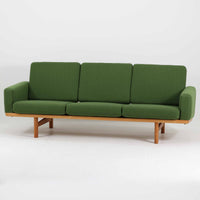 Hans J. Wegnerがデザインし、Getamaより製作されたGE236トリプルソファです。オーク材のフレームと直線を基調とした端正なフォルムが美しく、背面に配された横桟の意匠は後ろ姿まで印象的に演出します。ゆったりとした3人掛けの座面とクッションは快適な座り心地を実現し、リビングの主役として存在感を放ちます。ウェグナーらしい機能美と職人技が息づく設計に加え、経年により深みを増した木肌の風合いが北欧ビンテージならではの魅力を引き立てる希少な一台です。