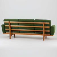Hans J. Wegnerがデザインし、Getamaより製作されたGE236トリプルソファです。オーク材のフレームと直線を基調とした端正なフォルムが美しく、背面に配された横桟の意匠は後ろ姿まで印象的に演出します。ゆったりとした3人掛けの座面とクッションは快適な座り心地を実現し、リビングの主役として存在感を放ちます。ウェグナーらしい機能美と職人技が息づく設計に加え、経年により深みを増した木肌の風合いが北欧ビンテージならではの魅力を引き立てる希少な一台です。