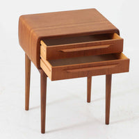 Johannes Andersen(ヨハネス・アンダーセン)がCFC Silkeborgのために手掛けた2段チェストは、チーク材を贅沢に用いた柔らかな曲面フォルムと長く伸びた彫刻的なハンドルが印象的で、天板から側面へと美しくつながる木目が上質な素材感を際立たせる北欧ビンテージ家具です。職人技の光る滑らかな面取りや端正な造りが深い味わいを生み出し、コンパクトながら実用的な2杯の引き出しを備え、ベッドサイドやリビングのサイドテーブルとしても活躍し、温かみのある木肌の経年変化が魅力を一層引き立てています。