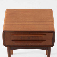 Johannes Andersen(ヨハネス・アンダーセン)がCFC Silkeborgのために手掛けた2段チェストは、チーク材を贅沢に用いた柔らかな曲面フォルムと長く伸びた彫刻的なハンドルが印象的で、天板から側面へと美しくつながる木目が上質な素材感を際立たせる北欧ビンテージ家具です。職人技の光る滑らかな面取りや端正な造りが深い味わいを生み出し、コンパクトながら実用的な2杯の引き出しを備え、ベッドサイドやリビングのサイドテーブルとしても活躍し、温かみのある木肌の経年変化が魅力を一層引き立てています。