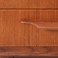 Johannes Andersen(ヨハネス・アンダーセン)がCFC Silkeborgのために手掛けた2段チェストは、チーク材を贅沢に用いた柔らかな曲面フォルムと長く伸びた彫刻的なハンドルが印象的で、天板から側面へと美しくつながる木目が上質な素材感を際立たせる北欧ビンテージ家具です。職人技の光る滑らかな面取りや端正な造りが深い味わいを生み出し、コンパクトながら実用的な2杯の引き出しを備え、ベッドサイドやリビングのサイドテーブルとしても活躍し、温かみのある木肌の経年変化が魅力を一層引き立てています。