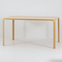 フィンランドを代表する建築家アルヴァ・アアルトによるデザイン、Artek社製の「X-leg」ダイニングテーブルです。素材には温かみのあるバーチ材を使用し、アアルトの象徴でもある積層合板による柔らかな曲線脚が特徴です。角のない優しいフォルムとシンプルな構造美が調和し、北欧デザインの真髄を感じさせます。経年によるバーチ材の飴色の風合いが美しく、空間に軽やかで穏やかな印象を与える一台です。