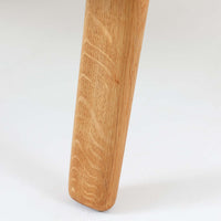 Hans J. Wegnerがデザインし、Getama社によって製作されたGE290は、構造の美しさと快適な座り心地を兼ね備えた北欧ビンテージを代表するシングルソファです。厚みのあるクッションと緩やかに傾斜した背もたれが身体を包み込み、自然と深いリラックス姿勢へと導きます。クッション内部にはビンテージ品ならではのスプリングが内包されており、しっかりとした弾力と安定感のある座り心地を生み出しています。オーク材のフレームは力強さと温かみを併せ持ち、アームから脚部にかけての造形にはウェグナーらしい彫刻的な魅力が感じられます。張地の落ち着いた色合いと、経年により深みを増した木部の表情が調和し、リビングや書斎で長く寄り添う一脚です。