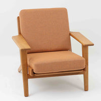 Hans J. Wegnerがデザインし、Getama社によって製作されたGE290は、構造の美しさと快適な座り心地を兼ね備えた北欧ビンテージを代表するシングルソファです。厚みのあるクッションと緩やかに傾斜した背もたれが身体を包み込み、自然と深いリラックス姿勢へと導きます。クッション内部にはビンテージ品ならではのスプリングが内包されており、しっかりとした弾力と安定感のある座り心地を生み出しています。オーク材のフレームは力強さと温かみを併せ持ち、アームから脚部にかけての造形にはウェグナーらしい彫刻的な魅力が感じられます。張地の落ち着いた色合いと、経年により深みを増した木部の表情が調和し、リビングや書斎で長く寄り添う一脚です。