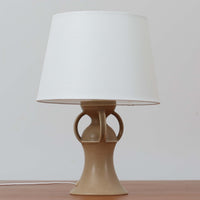 1993年にLe Klint創業50周年を記念して制作された、限定モデルのテーブルランプ「309」。ベースにはボーンホルム島の名門陶器工房Soholm(スーホルム)製のストーンウェアを採用し、シェードはLe Klint社製ではありませんが、新品のリネン製プリーツシェードを合わせており、クラシカルな佇まいと柔らかな光を演出します。北欧らしい温かみと洗練された存在感を持ち、ベッドサイドやリビングのアクセントとして取り入れやすい一灯です。ランプ底面には限定番号(No.0754)が刻まれており、コレクターズアイテムとしても価値ある一品です。