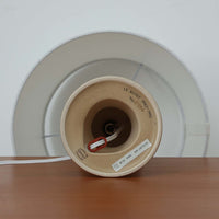 1993年にLe Klint創業50周年を記念して制作された、限定モデルのテーブルランプ「309」。ベースにはボーンホルム島の名門陶器工房Soholm(スーホルム)製のストーンウェアを採用し、シェードはLe Klint社製ではありませんが、新品のリネン製プリーツシェードを合わせており、クラシカルな佇まいと柔らかな光を演出します。北欧らしい温かみと洗練された存在感を持ち、ベッドサイドやリビングのアクセントとして取り入れやすい一灯です。ランプ底面には限定番号(No.0754)が刻まれており、コレクターズアイテムとしても価値ある一品です。