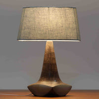 Michael Andersen & Sonが手掛けたこちらのテーブルランプは、陶磁器ならではの落ち着いた質感と、彫刻的に立ち上がるフォルムが存在感を放つ北欧ビンテージ品で、マットブラウンから生成り色へと移ろう釉薬のグラデーションが温かみある陰影を生み出し、リネンシェードを通したやわらかな灯りがベッドサイドやリビングに静かな安らぎを添えます。経年で深まった陶肌の表情がひとつとして同じものがない魅力となり、空間のアクセント照明として長くお楽しみいただける一台です。