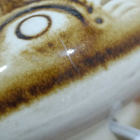 Soholm Keramik(スーホルム・セラミック)が手掛けたこちらのテーブルランプは、柔らかなクリーム色を基調にブラウンの縦流れ模様と円形のレリーフ装飾があしらわれた温かみある陶磁器ベースが魅力で、ふっくらと広がるフォルムが北欧ビンテージらしいやさしい存在感を放つ一台です。リネンシェード越しに灯る穏やかな光はベッドサイドやリビングの間接照明として心地よく空間を包み込み、経年で深まった釉薬の表情が一点物ならではの味わいを引き立てています。