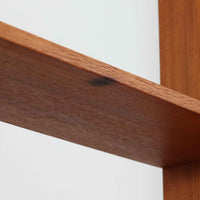 スウェーデン製のこちらのオープンシェルフは、チーク材の温かな木目とオーク材の脚部を組み合わせた軽やかな佇まいが魅力で、上段の棚板と下段のスライド扉収納を備えた実用性の高い構成が特徴の北欧ビンテージ家具です。丸い掘り込み取手や細身のフレームなど繊細なディテールが空間を柔らかく彩り、本や雑貨、食器などを美しく見せながら整頓でき、経年で深まった木肌の風合いがインテリアに落ち着きと温もりを与える一台です。