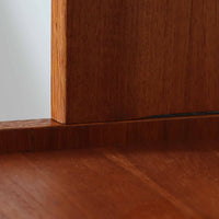 スウェーデン製のこちらのオープンシェルフは、チーク材の温かな木目とオーク材の脚部を組み合わせた軽やかな佇まいが魅力で、上段の棚板と下段のスライド扉収納を備えた実用性の高い構成が特徴の北欧ビンテージ家具です。丸い掘り込み取手や細身のフレームなど繊細なディテールが空間を柔らかく彩り、本や雑貨、食器などを美しく見せながら整頓でき、経年で深まった木肌の風合いがインテリアに落ち着きと温もりを与える一台です。