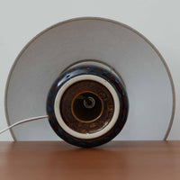 Einar JohansenがSoholm Keramik(スーホルム・セラミック)のために手掛けたモデル1015は、深いブラウンの釉薬に美しい光沢が宿り、ベースを覆う羽根模様のようなレリーフが立体的な表情を生み出す北欧ビンテージの名品で、すっきりと立ち上がるシルエットと陶磁器ならではの重厚感が空間に落ち着いた存在感をもたらします。リネンシェードを通したやわらかな灯りはベッドサイドやリビングに 温かみを添え、経年の風合いが一点物としての魅力をより一層引き立てています。