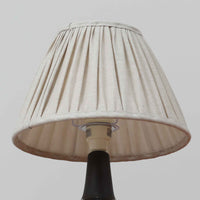 Einar JohansenがSoholm Keramik(スーホルム・セラミック)のためにデザインしたモデル1031は、深みのあるブルーの釉薬と立体的な面取りが織りなす陰影が美しい陶磁器ベースが特徴で、上部のマットな質感との対比がモダンで彫刻的な存在感を放つ北欧ビンテージ品です。プリーツシェードを透ける柔らかな灯りが落ち着いた雰囲気をつくり、ベッドサイドやリビングのアクセント照明として取り入れやすく、経年で深まった釉薬の表情が一点物ならではの魅力を一層引き立てています。