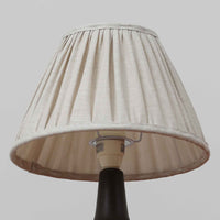 Einar JohansenがSoholm Keramik(スーホルム・セラミック)のためにデザインしたモデル1031は、深みのあるブルーの釉薬と立体的な面取りが織りなす陰影が美しい陶磁器ベースが特徴で、上部のマットな質感との対比がモダンで彫刻的な存在感を放つ北欧ビンテージ品です。プリーツシェードを透ける柔らかな灯りが落ち着いた雰囲気をつくり、ベッドサイドやリビングのアクセント照明として取り入れやすく、経年で深まった釉薬の表情が一点物ならではの魅力を一層引き立てています。