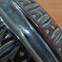 Einar JohansenがSoholm Keramik(スーホルム・セラミック)のために手掛けたモデル1038は、深みのあるブルーの釉薬が重なり合うように陰影をつくる陶磁器ベースと、上部のマットな質感とのコントラストが美しい北欧ビンテージ品で、四面に施された力強いレリーフ装飾が彫刻的な存在感を与えます。リネンシェード越しに広がる柔らかな灯りが空間を優しく包み込み、リビングやベッドサイドのアクセント照明として取り入れやすく、経年で深まった釉薬の表情が一点物ならではの味わいを一層引き立てています。