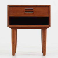 デンマーク製のサイドチェストで、シンプルなボックス構成にチーク材の豊かな風合いが映える北欧ビンテージらしい一台です。オープンスペースは本や小物の収納に便利で、引き出しには金属フレームを組み合わせたユニークな取手がアクセントとして効いています。丸みを帯びた角や細く伸びたテーパードレッグが軽快な印象を与え、ベッドサイドやソファ横でのサイドテーブル使いにも最適。経年変化の味わい深い木肌が空間に温かさと上質さを添えます。