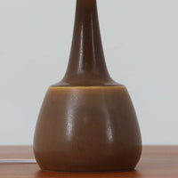 Per Lindemann SchmidtがPalshusのために手掛けたモデル「PL-5 SL 2」は、均整の取れたシルエットと滑らかに焼き締められたマットブラウンの陶肌が静かな存在感を放つテーブルランプで、首元にほんのり入る明るい釉薬のグラデーションが柔らかな表情を添える北欧ビンテージ品です。プリーツシェード越しに広がる落ち着いた灯りはリビングやベッドサイドに心地よい温もりをもたらし、シンプルながら洗練された造形美と経年で深まった風合いを長く楽しめる一台です。