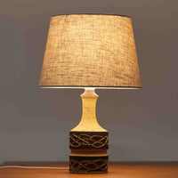 Jette HelleroeがAxellaのために手掛けたこちらのテーブルランプは、砂質の陶肌を生かした素朴で温かみのある質感と、ベース部分にぐるりと施された幾何学的なレリーフ装飾が印象的で、手仕事の風合いが際立つ北欧ビンテージ品です。すらりと立ち上がるシルエットが軽やかなバランスをつくり、リネンシェードを透ける柔らかな灯りがリビングやベッドサイドに落ち着いた雰囲気を添え、経年で深まった土味と装飾の陰影が一点物ならではの魅力を一層引き立てています。