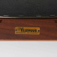 Kai Kristiansenがデザインし、Magnus Olesenが製作したTrojaアームチェアです。アフロモシア材の滑らかな木肌と深みのある色合いが美しく、背からアームへと一体で削り出されたフレームが身体をやさしく包み込みます。わずかに湾曲した笠木や細身の脚部が軽快な印象を与え、立ち座りの動作も自然。張り替え済みの座面は快適な掛け心地を備え、ダイニングや書斎空間に北欧ビンテージならではの気品と造形美をもたらす一脚です。ロゴは、デンマークの家具販売店(小売店)である Brdr. Ellehuus(エルフース兄弟店) のものです。