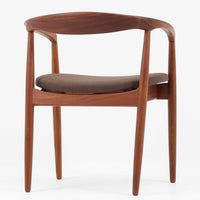 Kai Kristiansenがデザインし、Magnus Olesenが製作したTrojaアームチェアです。アフロモシア材の滑らかな木肌と深みのある色合いが美しく、背からアームへと一体で削り出されたフレームが身体をやさしく包み込みます。わずかに湾曲した笠木や細身の脚部が軽快な印象を与え、立ち座りの動作も自然。張り替え済みの座面は快適な掛け心地を備え、ダイニングや書斎空間に北欧ビンテージならではの気品と造形美をもたらす一脚です。ロゴは、デンマークの家具販売店(小売店)である Brdr. Ellehuus(エルフース兄弟店) のものです。