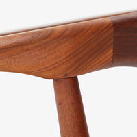 Kai Kristiansenがデザインし、Magnus Olesenが製作したTrojaアームチェアです。アフロモシア材の滑らかな木肌と深みのある色合いが美しく、背からアームへと一体で削り出されたフレームが身体をやさしく包み込みます。わずかに湾曲した笠木や細身の脚部が軽快な印象を与え、立ち座りの動作も自然。張り替え済みの座面は快適な掛け心地を備え、ダイニングや書斎空間に北欧ビンテージならではの気品と造形美をもたらす一脚です。ロゴは、デンマークの家具販売店(小売店)である Brdr. Ellehuus(エルフース兄弟店) のものです。