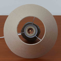 Chris HaslevがJetiのために手掛けたこちらのテーブルランプは、太陽を思わせるレリーフ模様をまとった陶器ベースと、素朴な土肌と釉薬の濃淡が織りなす豊かな表情が魅力で、コンパクトながら存在感を放つ北欧ビンテージ品です。上部のマットな質感が造形を引き締め、リネンシェード越しに広がるあたたかな灯りが空間をやさしく包み込み、リビングやベッドサイドのアクセントとして取り入れやすい一台に仕上がっています。