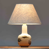 Nils Thorsson(ニルス・トールソン)によるRoyal Copenhagen(ロイヤルコペンハーゲン)の「DIANA」シリーズのテーブルランプは、白磁に繊細な草花や鳥の情景が描かれた静謐な佇まいが魅力で、淡い釉調が経年によりさらに深みを増したビンテージならではの味わいを感じさせます。柔らかく丸みを帯びたベースから伸びるすっきりとした首部のプロポーションが美しく、リネンシェードを通した穏やかな灯りが空間に上質な落ち着きを添えます。高さ32cmとコンパクトで取り入れやすく、ベッドサイドや読書灯としても活躍する、北欧陶芸の上品さが詰まった一台です。