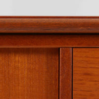 チーク材とビーチ材を組み合わせた北欧ビンテージらしい佇まいが魅力のディスプレイシェルフで、直線的で端正なフレーム構成と、木目の表情を活かした温かみのある質感が空間に落ち着きをもたらします。上部のオープン棚は器や書籍、オブジェの展示に適しており、下部には引き戸収納と引き出しを備えることで、見せる収納と隠す収納をバランス良く両立しています。脚付き構造により圧迫感が少なく、リビングやダイニング、書斎など幅広いシーンで活躍し、経年変化による色味の深まりも楽しめる一台です。