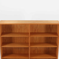 Borge Mogensenが手がけ、スウェーデンの老舗メーカーKarl Andersson & Sonerより製作されたOresundシリーズのブックシェルフです。オーク材の豊かな木目を全面に活かした構成で、無駄を削ぎ落とした端正なデザインからは、日常に根ざした家具を追求したモーエンセンらしい思想が感じられます。左右に分かれた棚構造は収納力に優れ、書籍はもちろん、器やオブジェなどもバランスよく配置可能。幅135cmのゆとりあるサイズ感と安定感のある造りは、リビングや書斎の主役として空間を引き締め、経年変化によって深みを増した素材感が北欧ビンテージならではの静かな存在感を添えます。