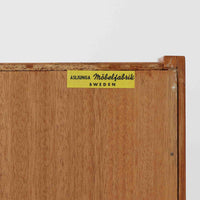 Asljunga Mobelfabrikによるディスプレイシェルフは、チーク材とビーチ材を組み合わせた端正な佇まいが魅力の北欧ビンテージ家具です。上段はオープンシェルフ構造で、棚板を活かした見せる収納が楽しめ、下段には引き戸式の収納部を備えることで実用性も確保されています。直線的で無駄のないフォルムに、掘り込み式の取っ手や脚部の軽やかなバランスが北欧らしい品の良さを添え、幅79cmの程よいサイズ感はリビングやダイニング、書斎など幅広い空間に取り入れやすく、経年変化によって深みを増した木肌と丁寧な造りが静かな存在感を放つ一台です。