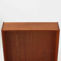 Asljunga Mobelfabrikによるディスプレイシェルフは、チーク材とビーチ材を組み合わせた端正な佇まいが魅力の北欧ビンテージ家具です。上段はオープンシェルフ構造で、棚板を活かした見せる収納が楽しめ、下段には引き戸式の収納部を備えることで実用性も確保されています。直線的で無駄のないフォルムに、掘り込み式の取っ手や脚部の軽やかなバランスが北欧らしい品の良さを添え、幅79cmの程よいサイズ感はリビングやダイニング、書斎など幅広い空間に取り入れやすく、経年変化によって深みを増した木肌と丁寧な造りが静かな存在感を放つ一台です。