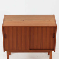 Asljunga Mobelfabrikによるディスプレイシェルフは、チーク材とビーチ材を組み合わせた端正な佇まいが魅力の北欧ビンテージ家具です。上段はオープンシェルフ構造で、棚板を活かした見せる収納が楽しめ、下段には引き戸式の収納部を備えることで実用性も確保されています。直線的で無駄のないフォルムに、掘り込み式の取っ手や脚部の軽やかなバランスが北欧らしい品の良さを添え、幅79cmの程よいサイズ感はリビングやダイニング、書斎など幅広い空間に取り入れやすく、経年変化によって深みを増した木肌と丁寧な造りが静かな存在感を放つ一台です。