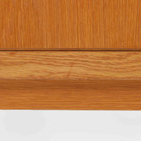 B. FridhagenがBodaforsのために手掛けたディスプレイシェルフは、端正なプロポーションと実用性を兼ね備えたスウェーデン製ビンテージ家具です。上部は抜け感のあるオープン棚構造で、器や書籍、オブジェなどを軽やかに飾ることができ、下部には4段の引き出しを備え、日常使いの収納にも対応します。オーク材ならではの明るく上品な木肌と、直線を基調とした構成が北欧らしい落ち着いた印象を生み、空間をすっきりとまとめてくれます。幅90cm、高さ122cmの小ぶりなサイズ感で、ダイニングやリビング、書斎など幅広いシーンに取り入れやすく、経年変化による木の表情も楽しめる一台です。