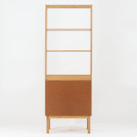 B. Fridhagenがデザインし、Bodafors社により1963年に製作されたスリムシェルフです。オーク材のやわらかな木目と明るい色合いが空間に温もりをもたらし、上部のオープン棚と下部の4段引き出しを備えた実用的な構成が魅力。幅63cmのすっきりとしたサイズで、書斎やリビングの一角にも取り入れやすい一台です。直線的で端正なフォルムと丁寧なつくりから、北欧ビンテージならではの機能美と経年の味わいを感じられる逸品です。