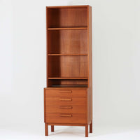 Nils Jonsson(ニールス・ヨンソン)がデザインし、Hugo Troeds(ヒューゴー・トロエッツ)社より製作されたDomi Monteシリーズのスリムシェルフです。良質なチーク材を用いた端正なキャビネットとオープンシェルフを組み合わせた構成で、収納力と見せるディスプレイ性を両立しています。直線を基調とした洗練されたフォルムと、引き出しに刻まれた繊細な手掛けが北欧らしい上品さを演出し、リビングや書斎、ダイニング収納としても活躍します。経年変化によって深みを増した木肌から、当時の職人技とビンテージならではの存在感が感じられる一台です。