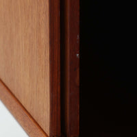 Nils Jonssonがデザインし、Hugo Troedsが製作した幅95cmの小ぶりなボードです。上質なチーク材を用いた端正な箱型フォルムに、楕円形の彫り込み取っ手がさりげないアクセントを添えています。引き戸仕様により限られた空間でも扱いやすく、内部には棚板を備え収納力も十分。すらりと伸びる脚部が軽やかな印象を与え、リビングや書斎、玄関先でも活躍します。経年により深みを増した木肌が北欧ビンテージならではの温もりと存在感を感じさせる一品です。