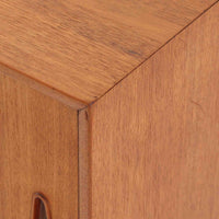 Nils Jonssonがデザインし、Hugo Troedsが製作した幅95cmの小ぶりなボードです。上質なチーク材を用いた端正な箱型フォルムに、楕円形の彫り込み取っ手がさりげないアクセントを添えています。引き戸仕様により限られた空間でも扱いやすく、内部には棚板を備え収納力も十分。すらりと伸びる脚部が軽やかな印象を与え、リビングや書斎、玄関先でも活躍します。経年により深みを増した木肌が北欧ビンテージならではの温もりと存在感を感じさせる一品です。